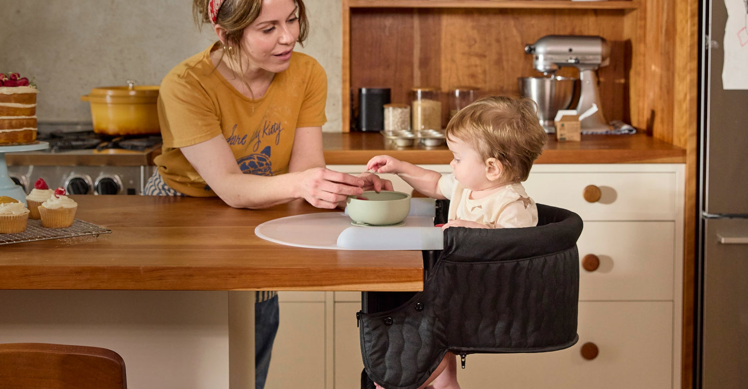 Woman and child in a kitchen with the woman feeding the child.
