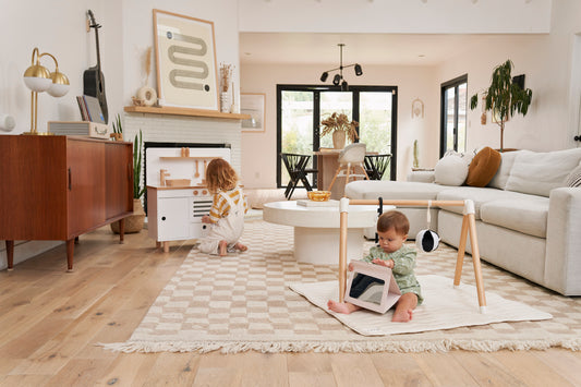 Baby girl sitting on the floor, opening gifts beside a big stuffed toy