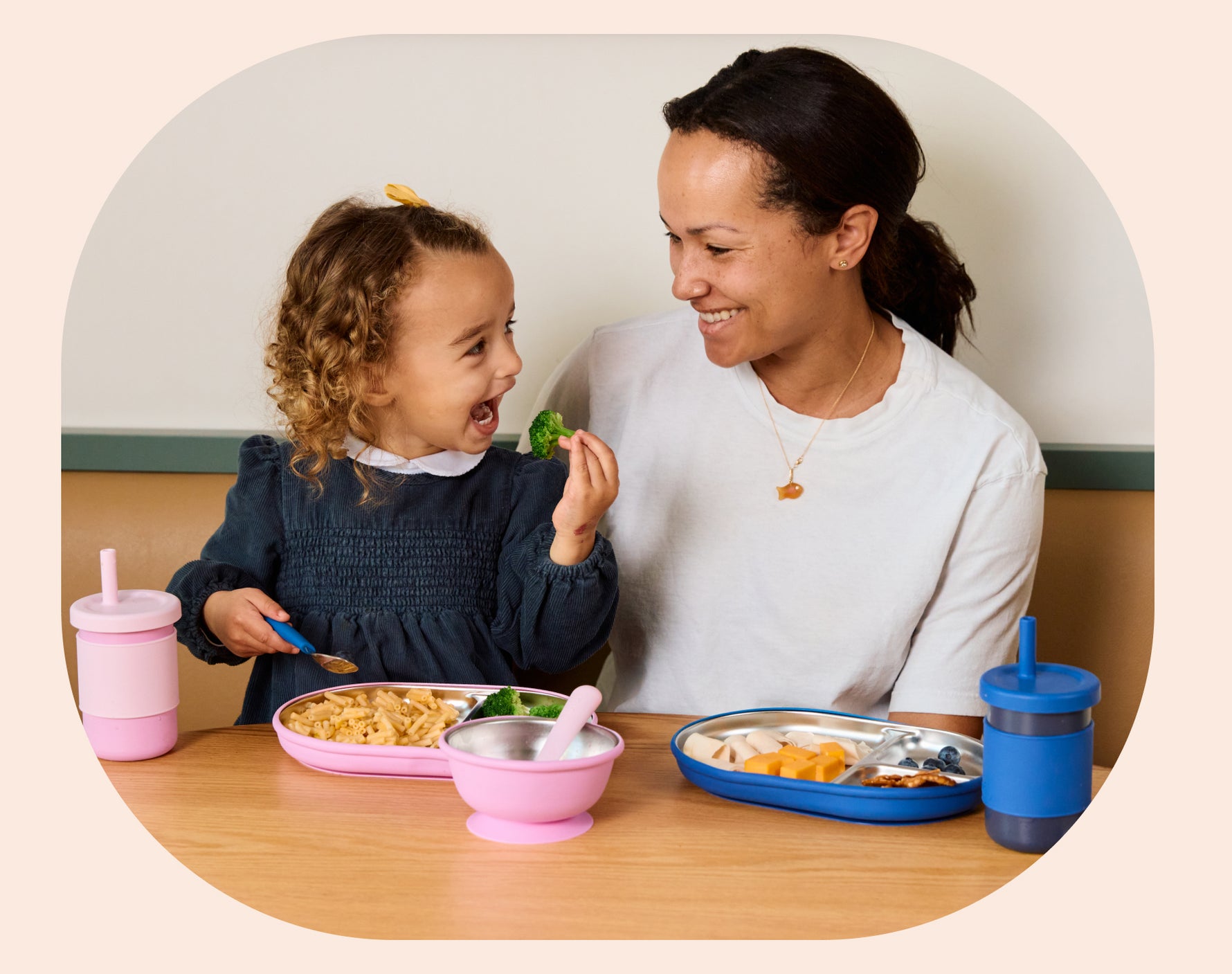 Woman and child eating together at a table with Lalo Stainless Steel Suction Plate, Suction Bowl and Toddler Cup.