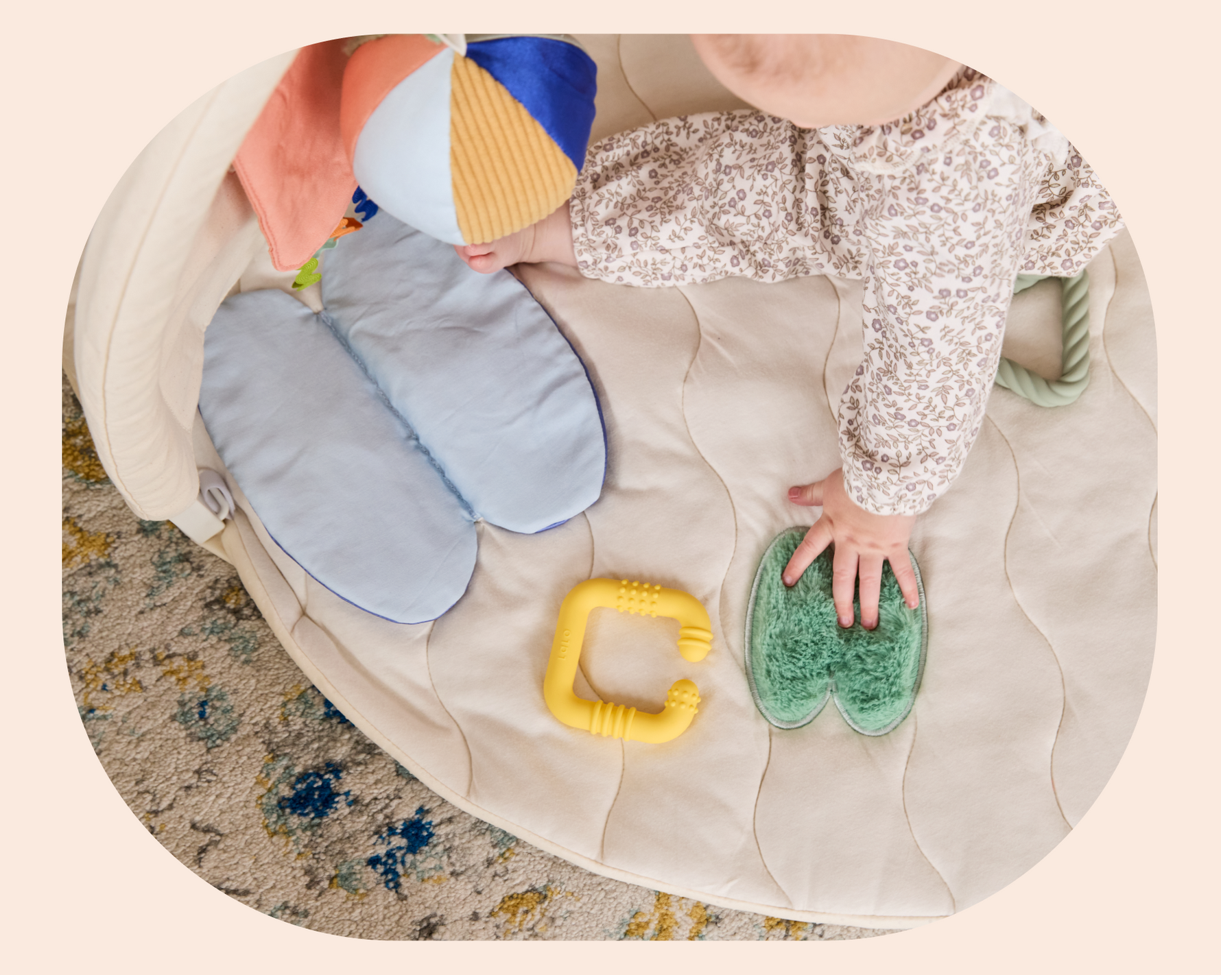 Baby playing with colorful toys on a soft play mat