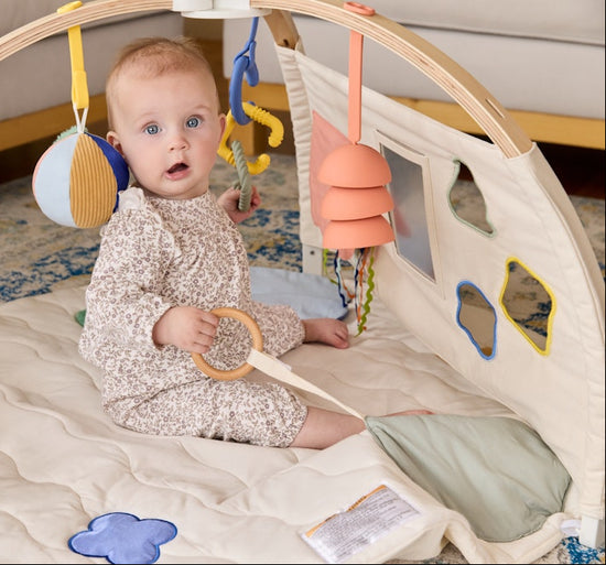 Baby sitting up and playing with the sit & play panel
